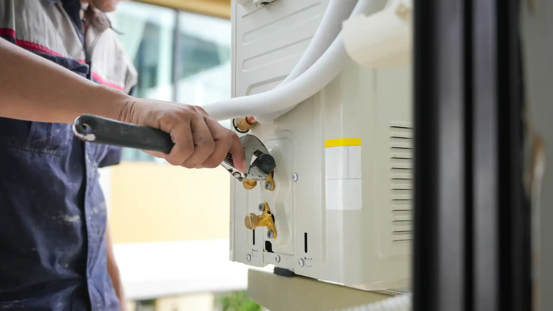Air condition technician working on an A/C unit with a adjustable wrench.