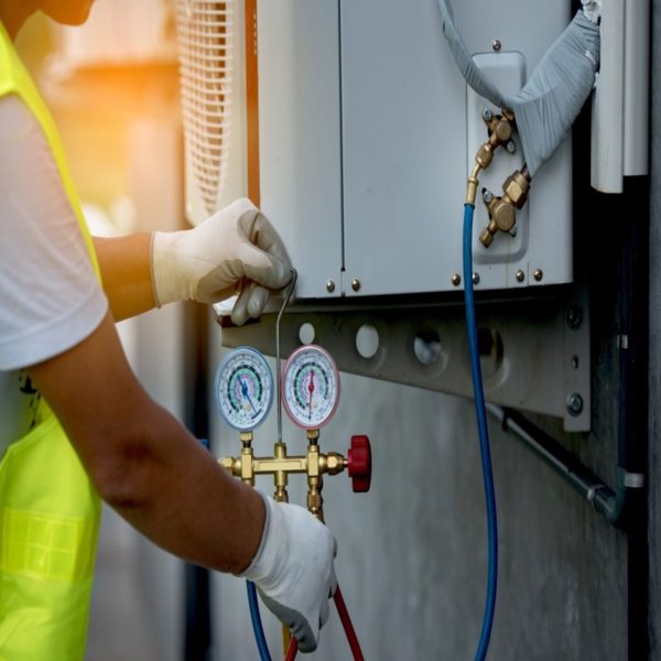 Technician adjusting refrigerant lines on an AC unit