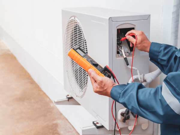 Technician testing outdoor AC unit wiring