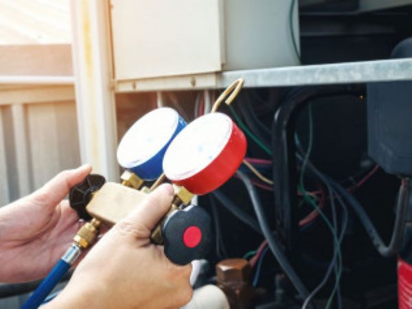 Technician using a manifold gauge set on an AC unit