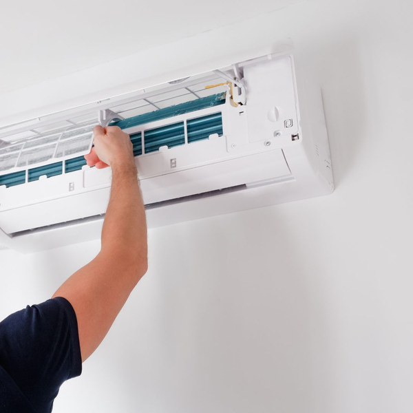 Person cleaning the filter of a wall-mounted air conditioner unit.
