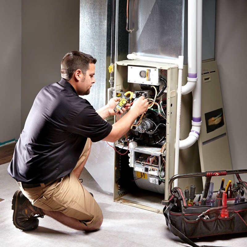 HVAC technician testing wiring inside a furnace