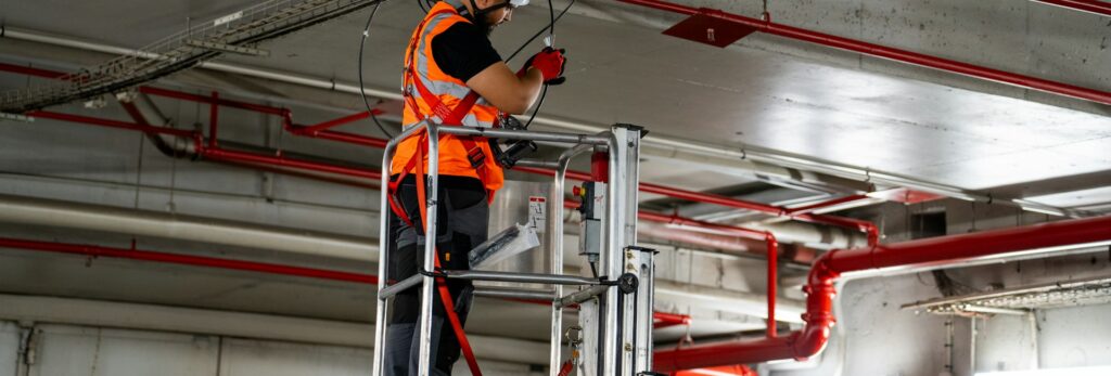 Technician on a lift installing overhead HVAC components