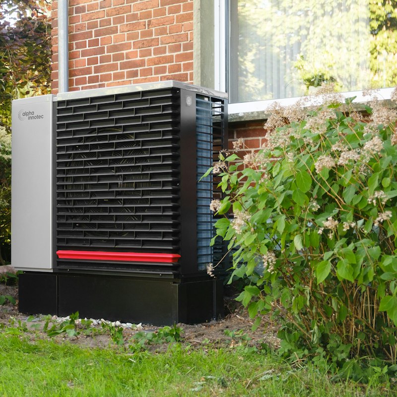 Outdoor heat pump unit beside a brick home